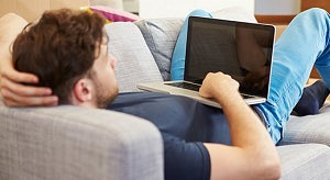 man lying on sofa with laptop