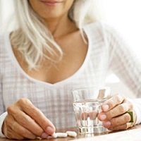 photo of woman holding supplement and water